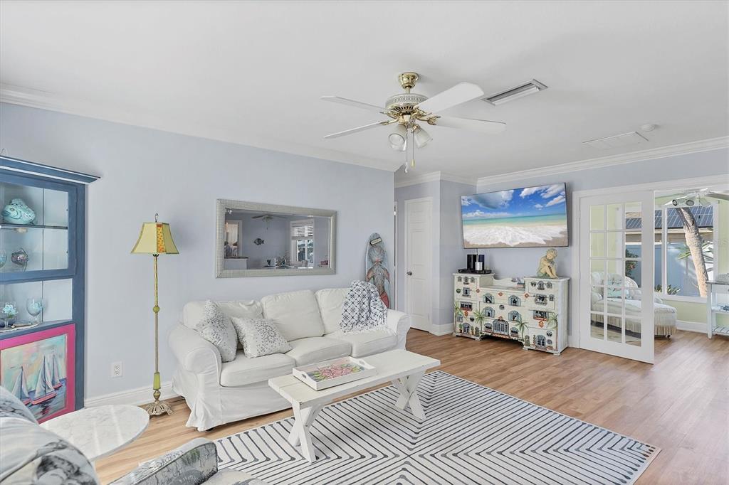 A living room features a white sofa, a geometric rug, and a television mounted above a dresser — 2745 ARROWHEAD ROAD, VENICE, FL