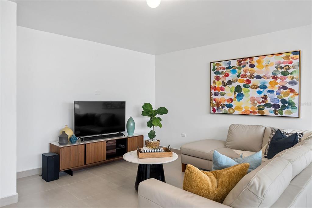 A living room features a beige sectional sofa, a wooden media console, and colorful wall art — 2 Condado Princess WASHINGTON STREET UNIT 103, SAN JUAN, PR