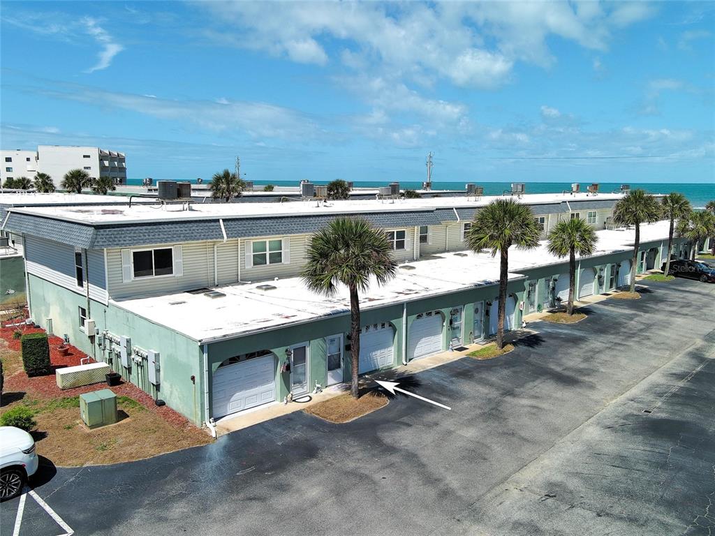 An aerial view shows a row of townhouses with garages and palm trees near the ocean — 2820 OCEAN SHORE BOULEVARD UNIT 150, ORMOND BEACH, FL