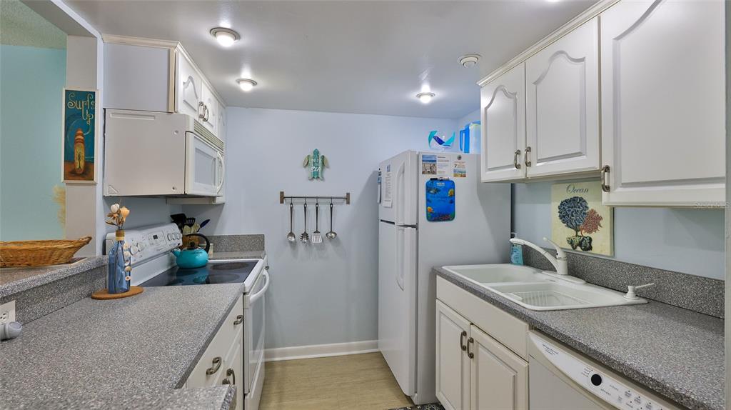 A kitchen features white cabinetry, gray countertops, a white refrigerator, and a white stove — 2820 OCEAN SHORE BOULEVARD UNIT 150, ORMOND BEACH, FL