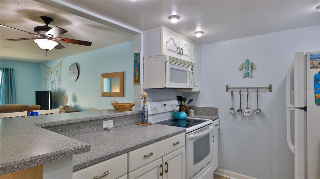 A kitchen features white cabinets, a gray countertop, a white stove, and a breakfast bar — 2820 OCEAN SHORE BOULEVARD UNIT 150, ORMOND BEACH, FL