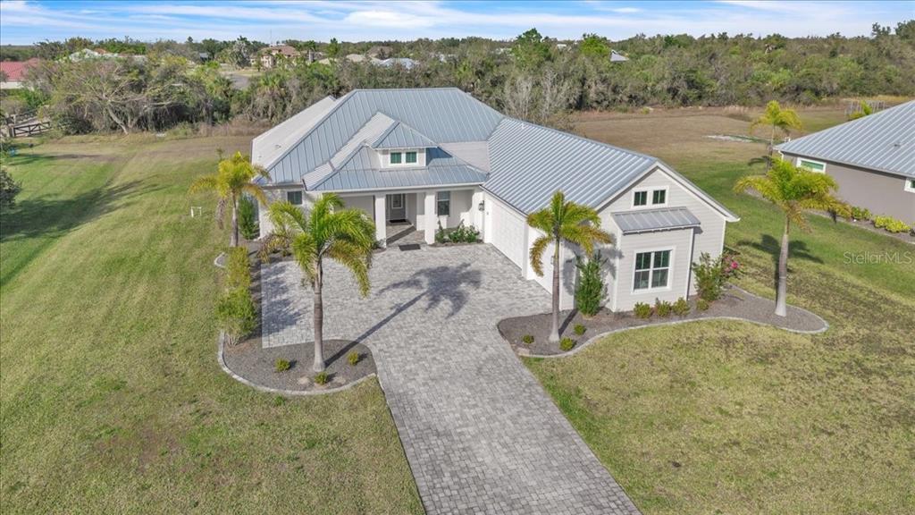 An aerial view shows a single-story house with a metal roof and paved driveway — 28960 GIN LANE, PUNTA GORDA, FL