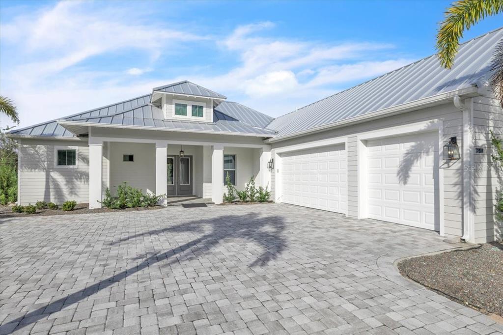 A single-story house with a metal roof, white siding, and a paved driveway — 28960 GIN LANE, PUNTA GORDA, FL