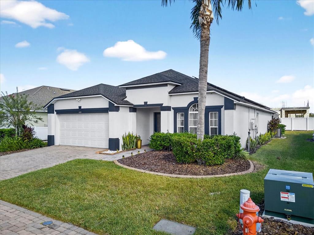 A single-story house with a white stucco exterior, dark trim, and a paved driveway — 654 KILDRUMMY DRIVE, DAVENPORT, FL