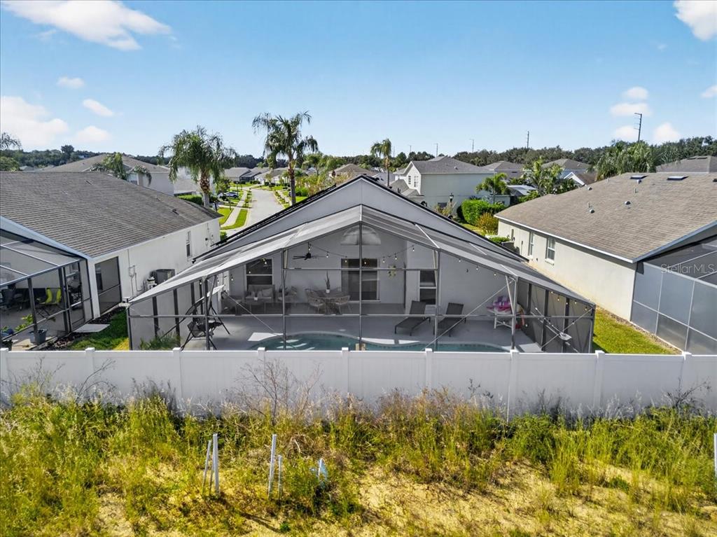 An aerial view of a house with a screened-in pool patio and white vinyl fence — 654 KILDRUMMY DRIVE, DAVENPORT, FL