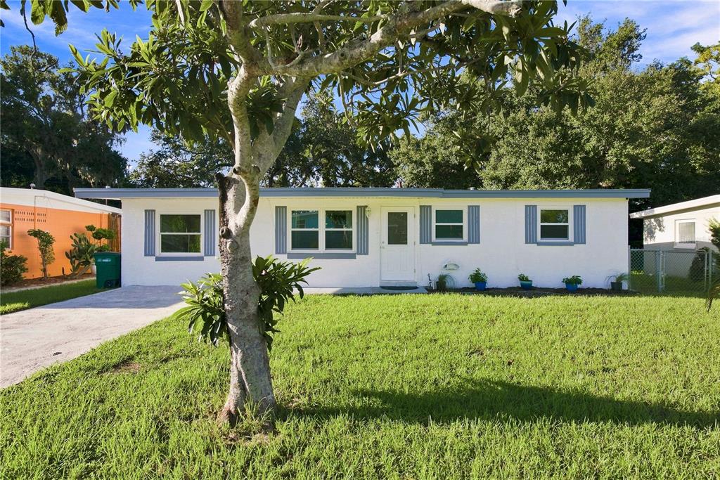 A single-story white house with blue shutters and a front lawn under a large tree — 1120 6TH STREET N, SAFETY HARBOR, FL