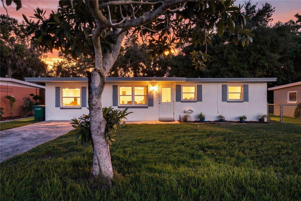 A single-story white house with a front lawn, a driveway, and a large tree — 1120 6TH STREET N, SAFETY HARBOR, FL