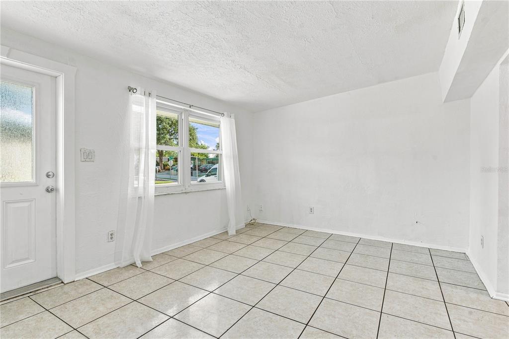 An empty room with white walls, tile flooring, a window with curtains, and a door — 1120 6TH STREET N, SAFETY HARBOR, FL