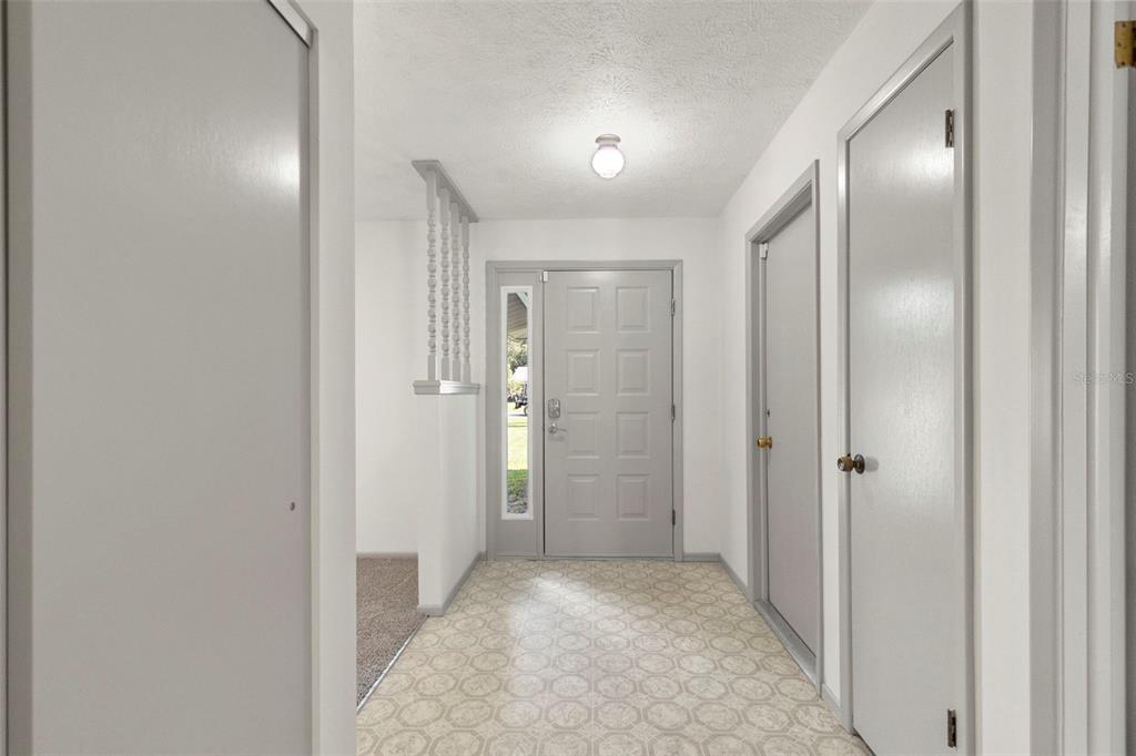 A foyer with a gray front door, tiled floor, and doors leading to adjacent rooms — 37216 ORANGE BLOSSOM LANE, DADE CITY, FL