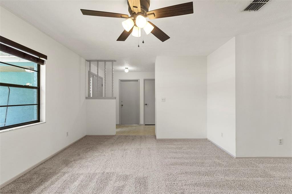 A carpeted living room features a ceiling fan, a window, and a partial wall divider — 37216 ORANGE BLOSSOM LANE, DADE CITY, FL
