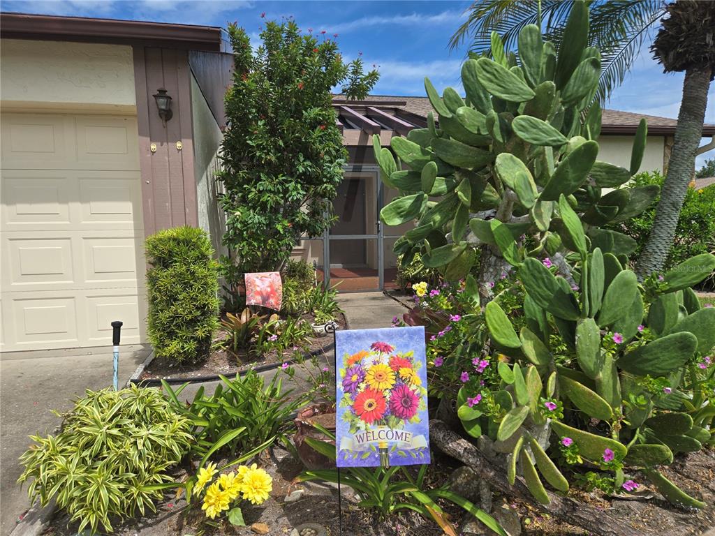 The exterior of a house features a garage, a front entrance, and a large cactus — 658 FOXWOOD BOULEVARD UNIT 88, ENGLEWOOD, FL