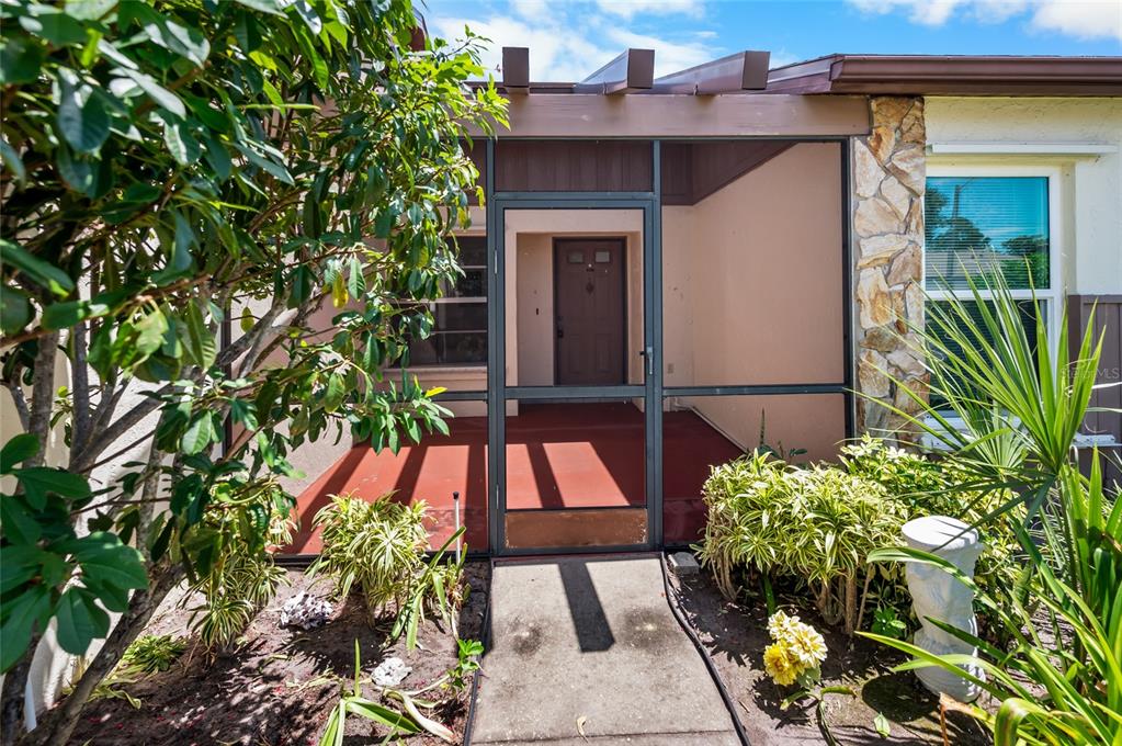 A screened-in front porch with a concrete walkway leads to a brown front door — 658 FOXWOOD BOULEVARD UNIT 88, ENGLEWOOD, FL