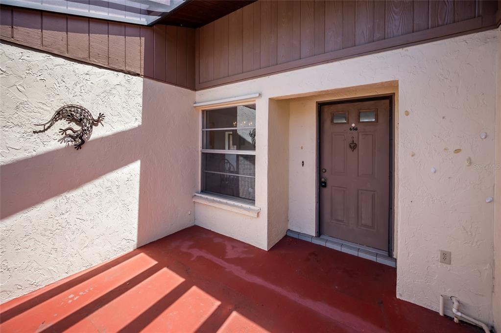 A front entryway features a red concrete porch, a brown door, and a metal lizard decoration — 658 FOXWOOD BOULEVARD UNIT 88, ENGLEWOOD, FL