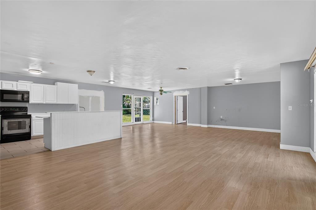 An open-concept kitchen and living area features light wood flooring and white cabinetry — 1220 HOWELL BRANCH ROAD, WINTER PARK, FL