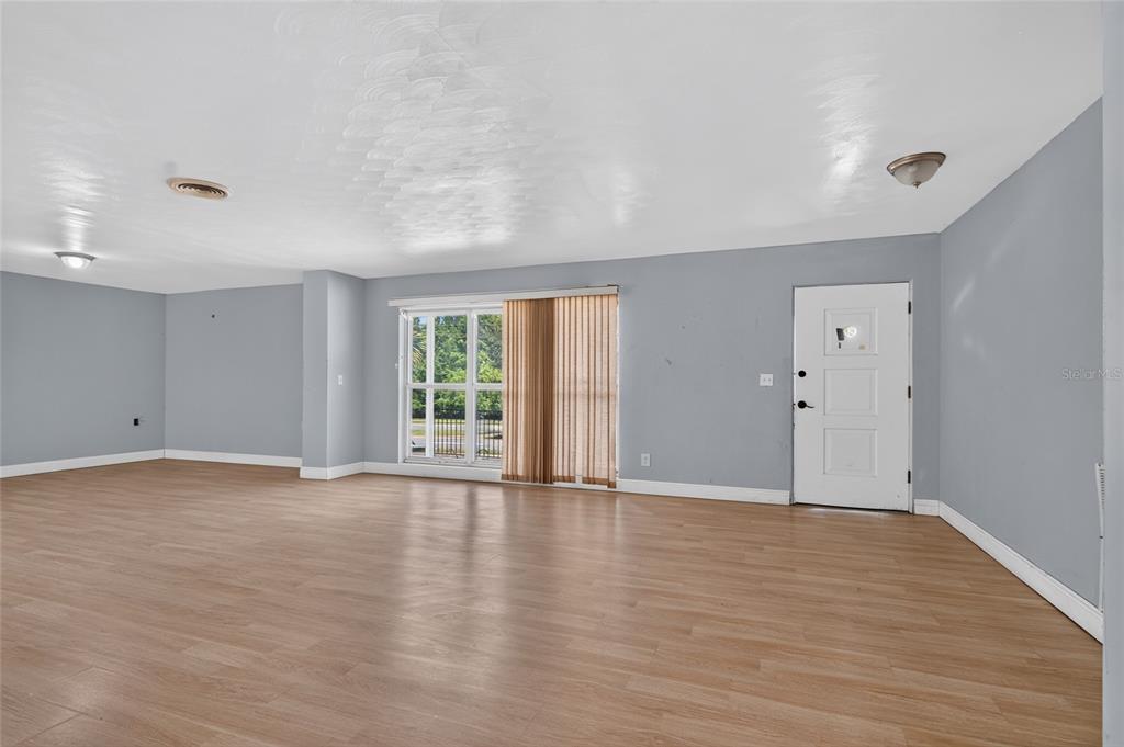 An empty room with light wood-look flooring, gray walls, a sliding glass door, and white trim — 1220 HOWELL BRANCH ROAD, WINTER PARK, FL