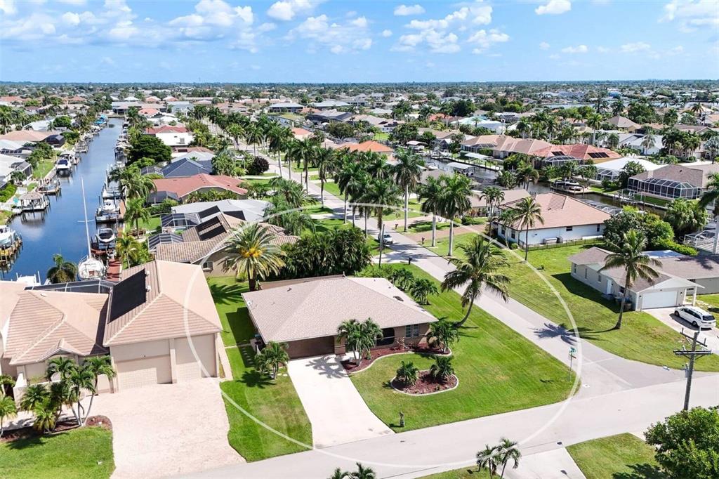 An aerial view of a suburban neighborhood featuring houses, palm trees, and a canal — 901 SW 51ST TERRACE, CAPE CORAL, FL