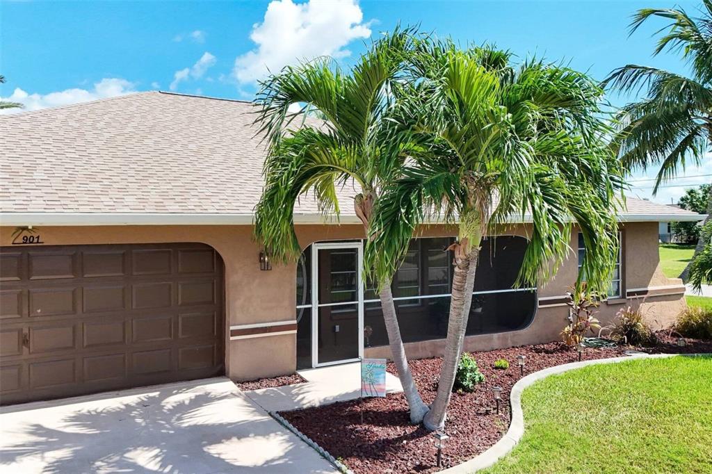 A tan house with a brown garage door and a palm tree in the front yard — 901 SW 51ST TERRACE, CAPE CORAL, FL