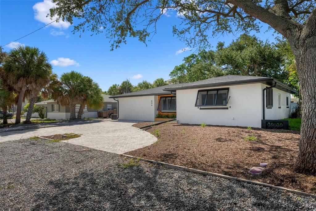 A single-story white house with a paved driveway and a large tree in the yard — 406 88TH AVENUE, ST PETE BEACH, FL