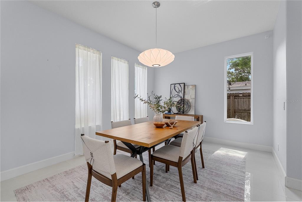 A dining room features a wooden table, six chairs, a pendant light, and large windows — 1404 BORDER DRIVE, WINTER PARK, FL