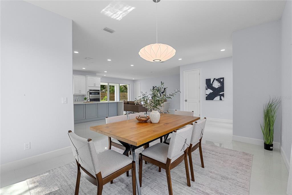 A dining area with a wooden table and chairs sits before an open-concept kitchen — 1404 BORDER DRIVE, WINTER PARK, FL