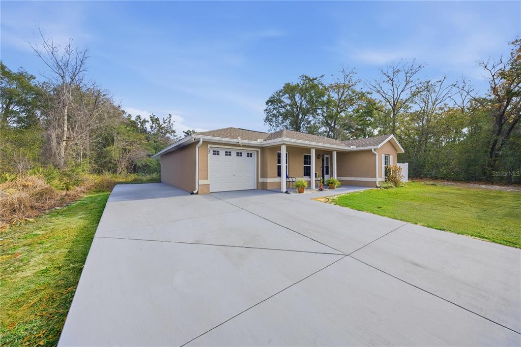 A single-story house with a tan stucco exterior, a one-car garage, and a concrete driveway — 157 SPRUCE ROAD, OCALA, FL