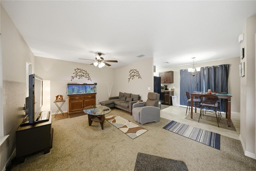 A living room with carpeted floors, a fish tank, a sofa, and an adjacent dining area — 157 SPRUCE ROAD, OCALA, FL