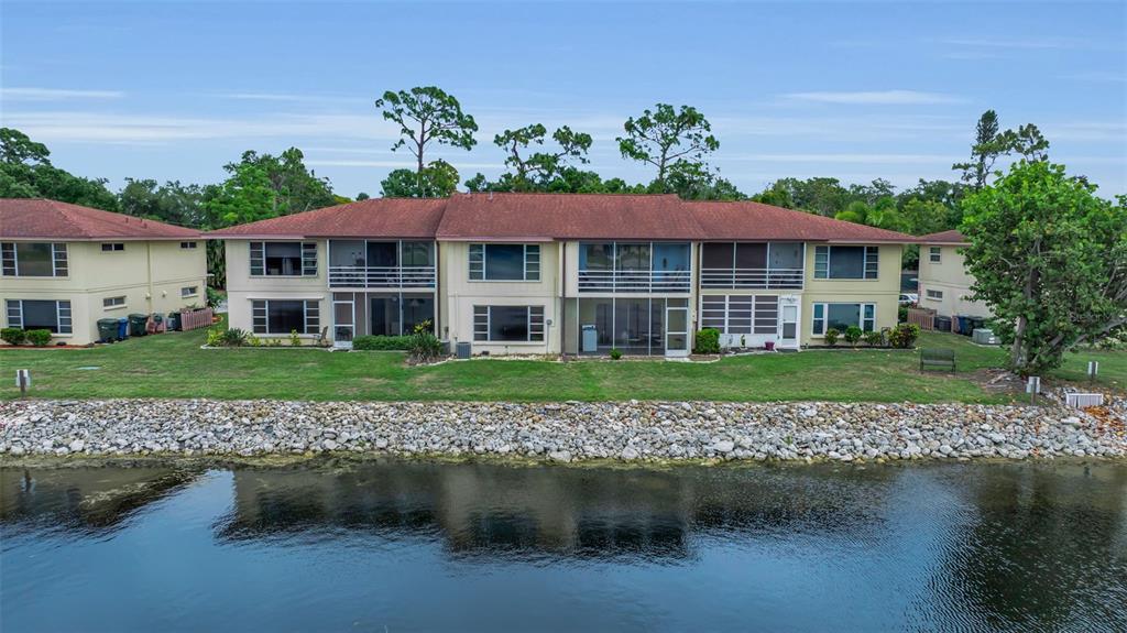A screened-in porch overlooks a lake with a small decorative lighthouse on a side table — 4470 NARRAGANSET TRAIL UNIT 90A, SARASOTA, FL