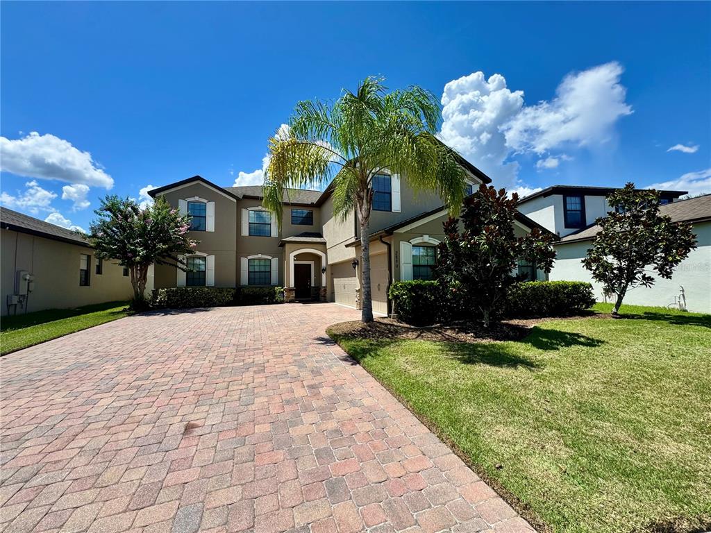 A two-story house with a brick paver driveway, a palm tree, and a grassy lawn — 2890 SPRING BREEZE WAY, KISSIMMEE, FL