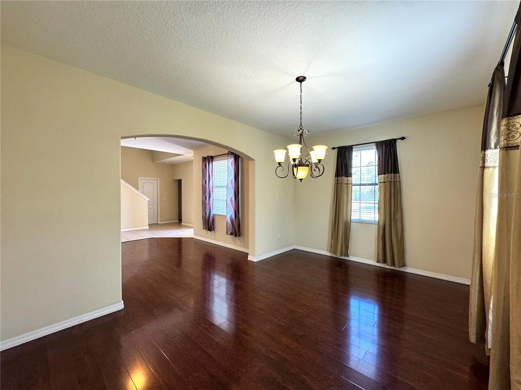 A dining room with dark hardwood floors, an arched entryway, and a chandelier — 2890 SPRING BREEZE WAY, KISSIMMEE, FL