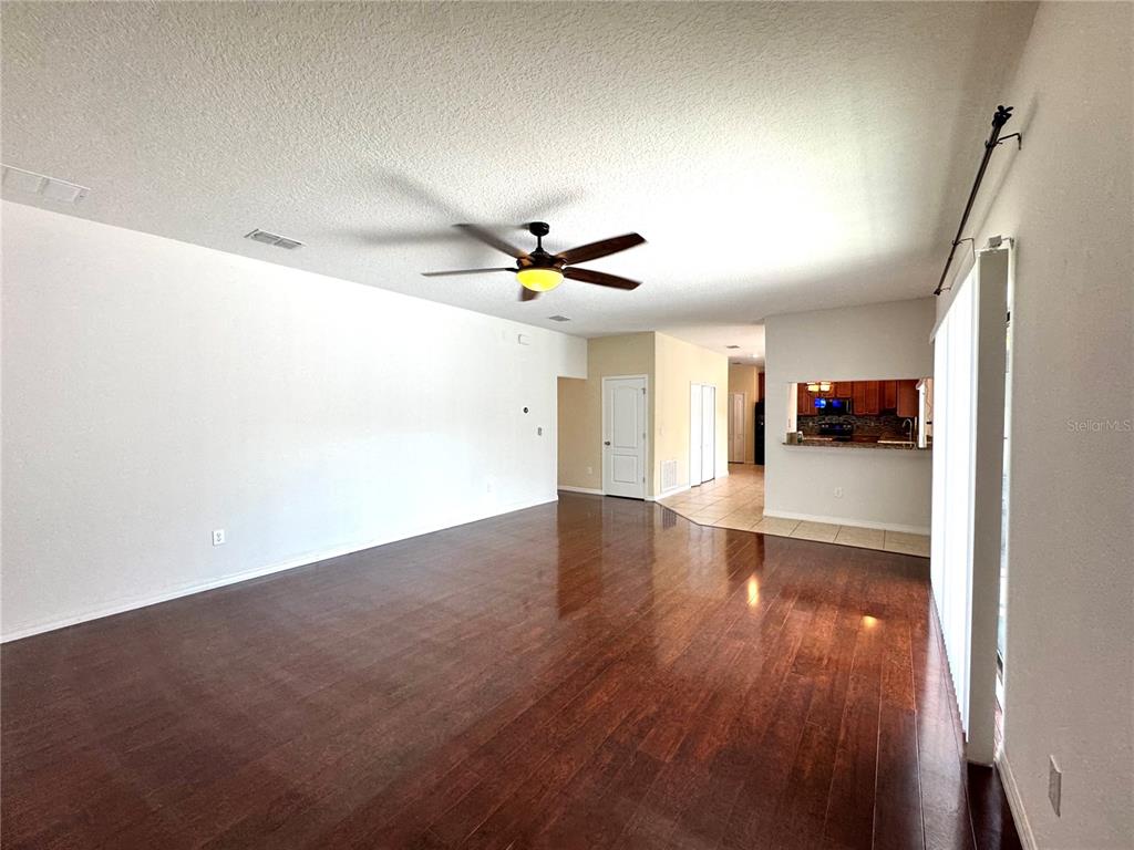 A living room with dark wood flooring, a ceiling fan, and an open kitchen pass-through — 2890 SPRING BREEZE WAY, KISSIMMEE, FL
