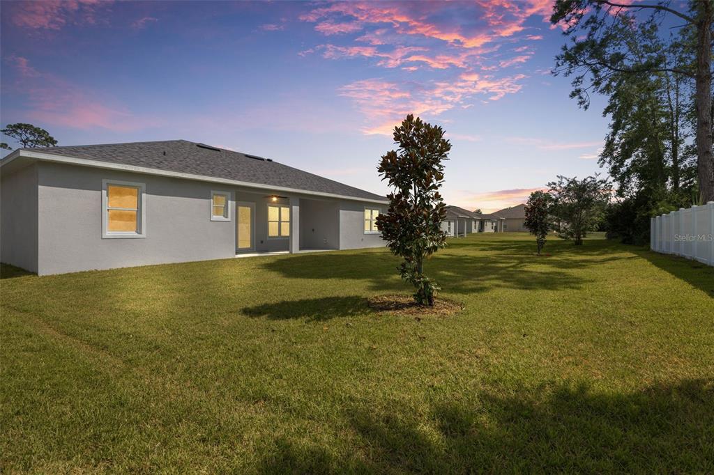 The exterior of a gray house with a large backyard and a small tree — 45 FARMSWORTH DRIVE, PALM COAST, FL