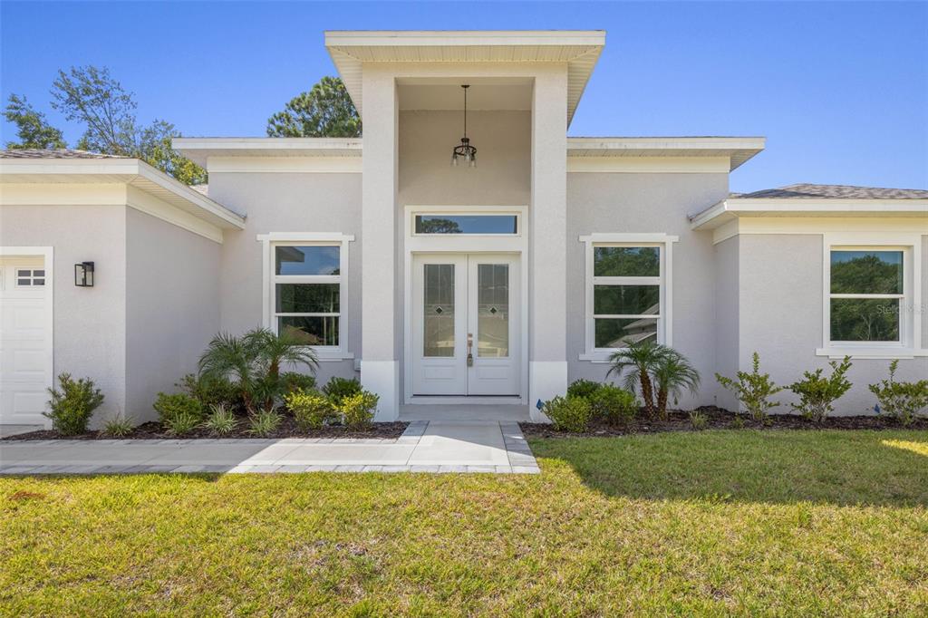 The exterior of a modern, light-colored single-story house with a prominent central entryway — 45 FARMSWORTH DRIVE, PALM COAST, FL