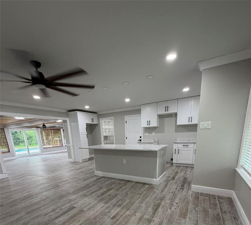 A kitchen with white cabinets, a marble-topped island, and wood-look tile flooring — 8715 DRIFTWOOD DRIVE, TAMPA, FL