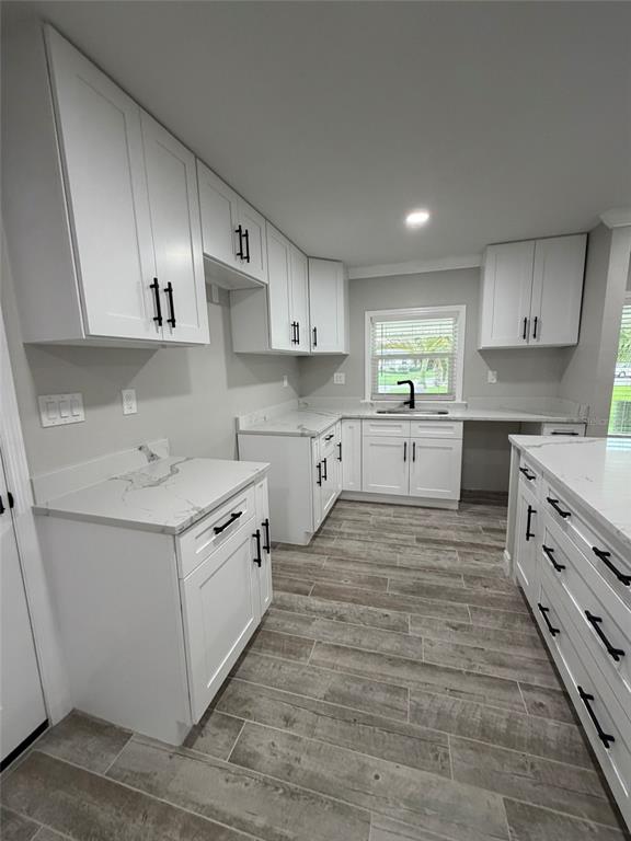 A modern kitchen features white shaker cabinets, marble-look countertops, and gray wood-look tile flooring — 8715 DRIFTWOOD DRIVE, TAMPA, FL