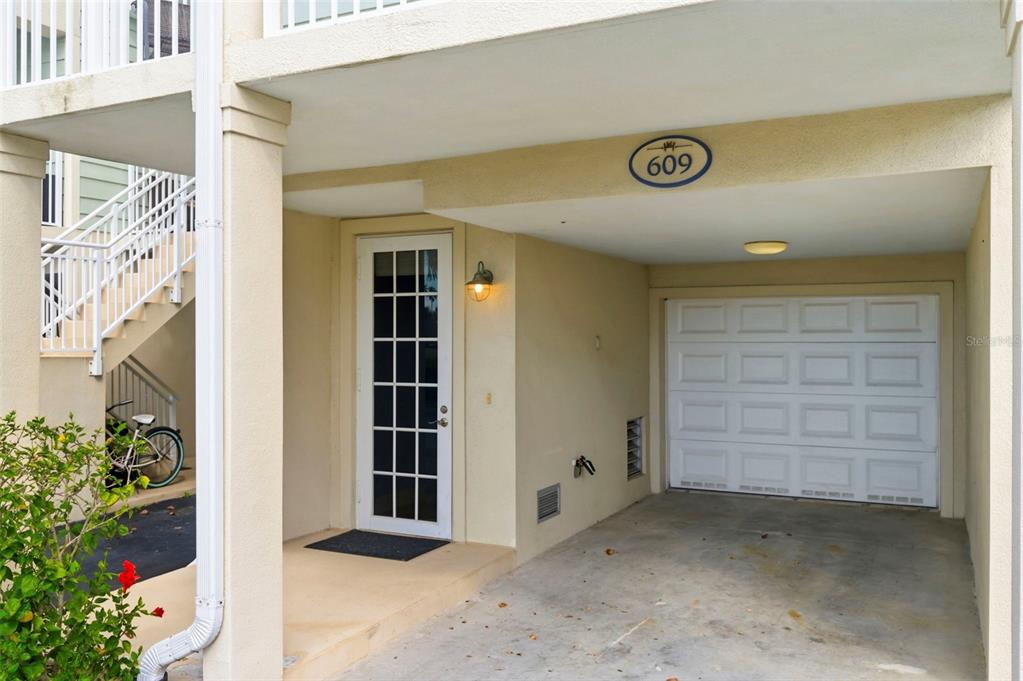 A ground-level view shows a covered carport, a white garage door, and a glass-paneled door — 609 BAHIA BEACH BOULEVARD, RUSKIN, FL