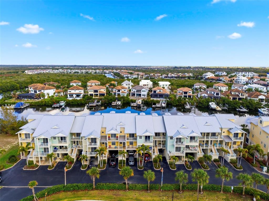 An aerial view shows a multi-unit residential building with metal roofs facing a canal — 609 BAHIA BEACH BOULEVARD, RUSKIN, FL