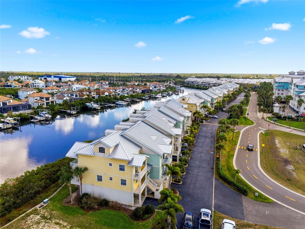 An aerial view shows a yellow multi-story residential building beside a canal with docked boats — 609 BAHIA BEACH BOULEVARD, RUSKIN, FL