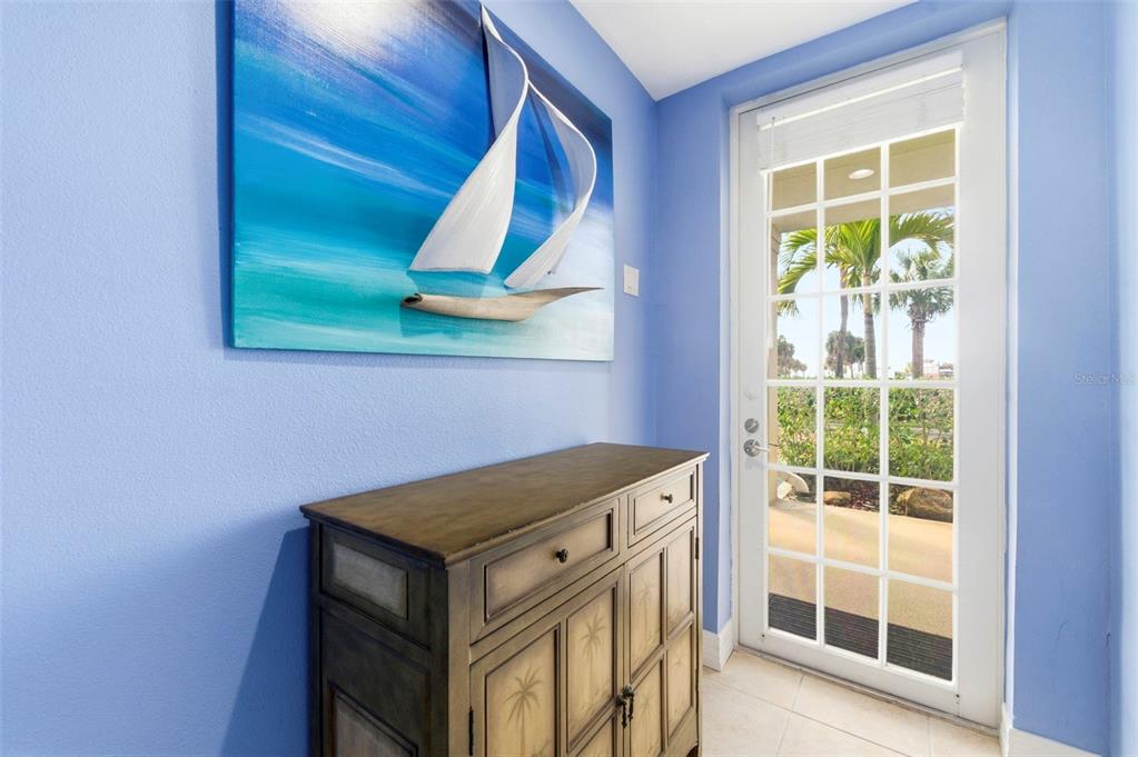 A blue-walled entryway features a wooden cabinet, a sailboat wall art piece, and a glass door — 609 BAHIA BEACH BOULEVARD, RUSKIN, FL