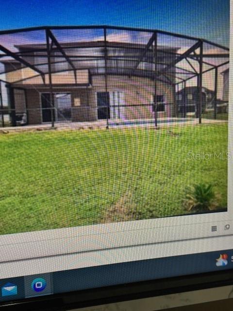 A two-story house with a screened-in pool enclosure sits behind a large grassy backyard — 5418 CALLA LILY COURT, KISSIMMEE, FL