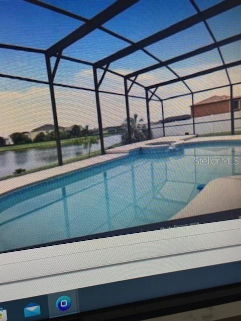 A screened-in swimming pool overlooks a lake and neighboring houses — 5418 CALLA LILY COURT, KISSIMMEE, FL