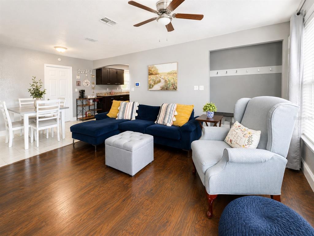 A living room with a blue sectional sofa, light blue armchair, and adjacent dining area — 1035 COBBLESTONE AVENUE, DELTONA, FL