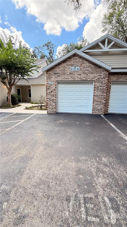 A brick-front residential building features two white garage doors under a gabled roof — 4700 SW ARCHER ROAD UNIT 26, GAINESVILLE, FL