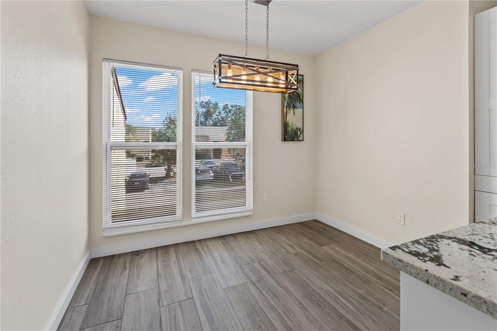 An empty living room features wood-look tile flooring, a ceiling fan, and sliding glass doors — 3405 CLARK ROAD UNIT 205, SARASOTA, FL
