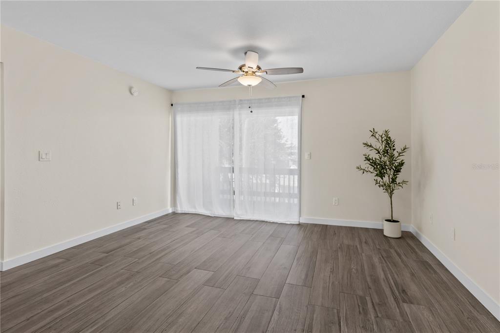 A living room with a television, sofa, armchair, coffee table, and a sliding glass door — 3405 CLARK ROAD UNIT 205, SARASOTA, FL