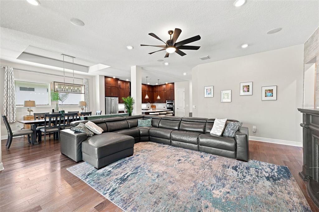 A living room with a large gray sectional sofa, area rug, and open-concept kitchen — 4070 EPIC COVE, LAND O LAKES, FL