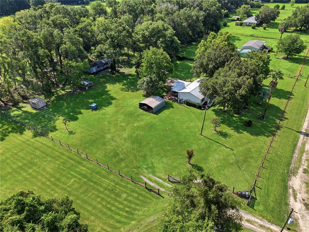 An aerial view shows a house, a carport, and several outbuildings on a large grassy lot — 22930 NW 50TH LANE, NEWBERRY, FL
