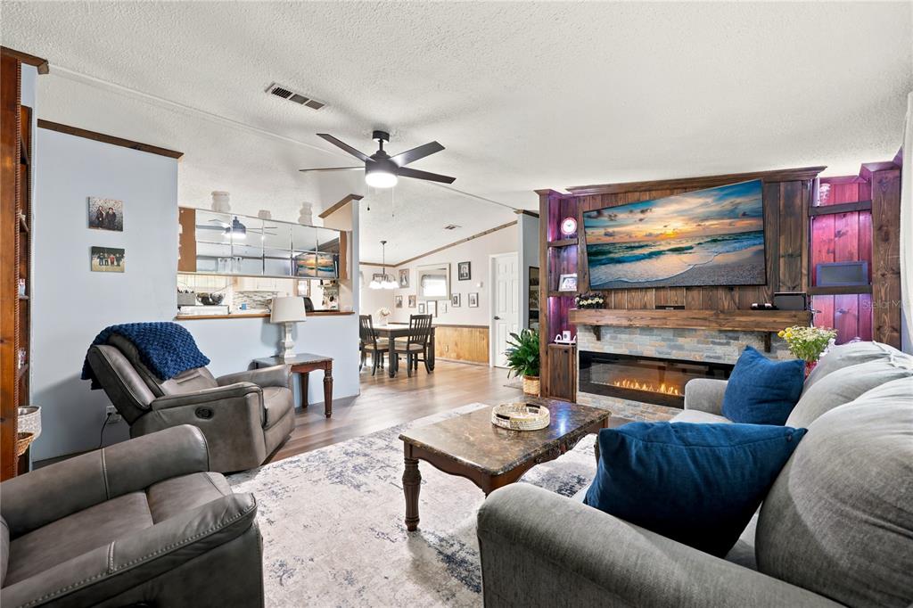 A living room features a stone fireplace, wood shelving, a ceiling fan, and gray furniture — 22930 NW 50TH LANE, NEWBERRY, FL