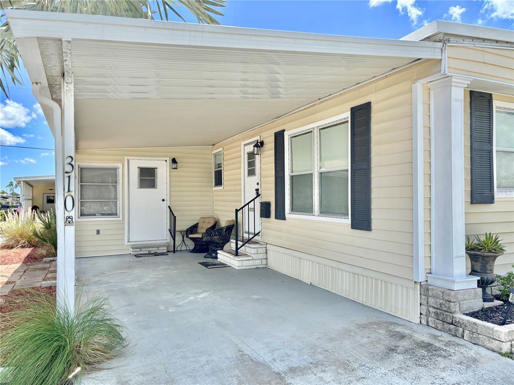 A light-colored mobile home features a covered carport, two entry doors, and a front window — 310 MOUNT PINEY AVENUE NE UNIT 266, ST PETERSBURG, FL