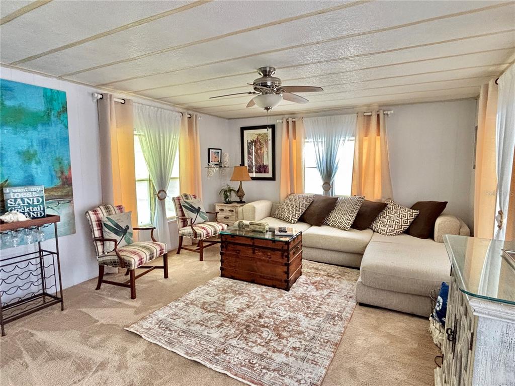 A living room features a sectional sofa, two patterned armchairs, a wooden chest, and carpet — 310 MOUNT PINEY AVENUE NE UNIT 266, ST PETERSBURG, FL
