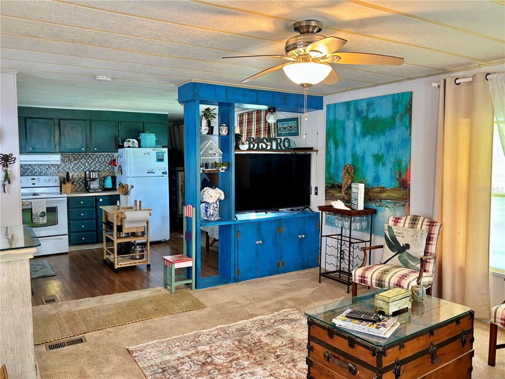 A living room with a blue media console and a kitchen with dark green cabinets — 310 MOUNT PINEY AVENUE NE UNIT 266, ST PETERSBURG, FL
